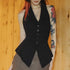 Person wearing a black vest with tattoos on arms against a wooden background